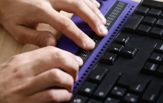 Close up of fingers on a refreshable braille display