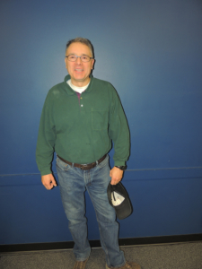 Jon Ott standing against a blue background.