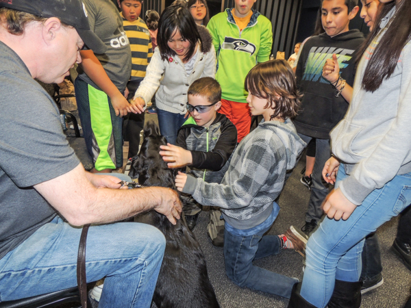 Students gathered around Lighthouse machinist Mike King and his guide dog during a School Tour