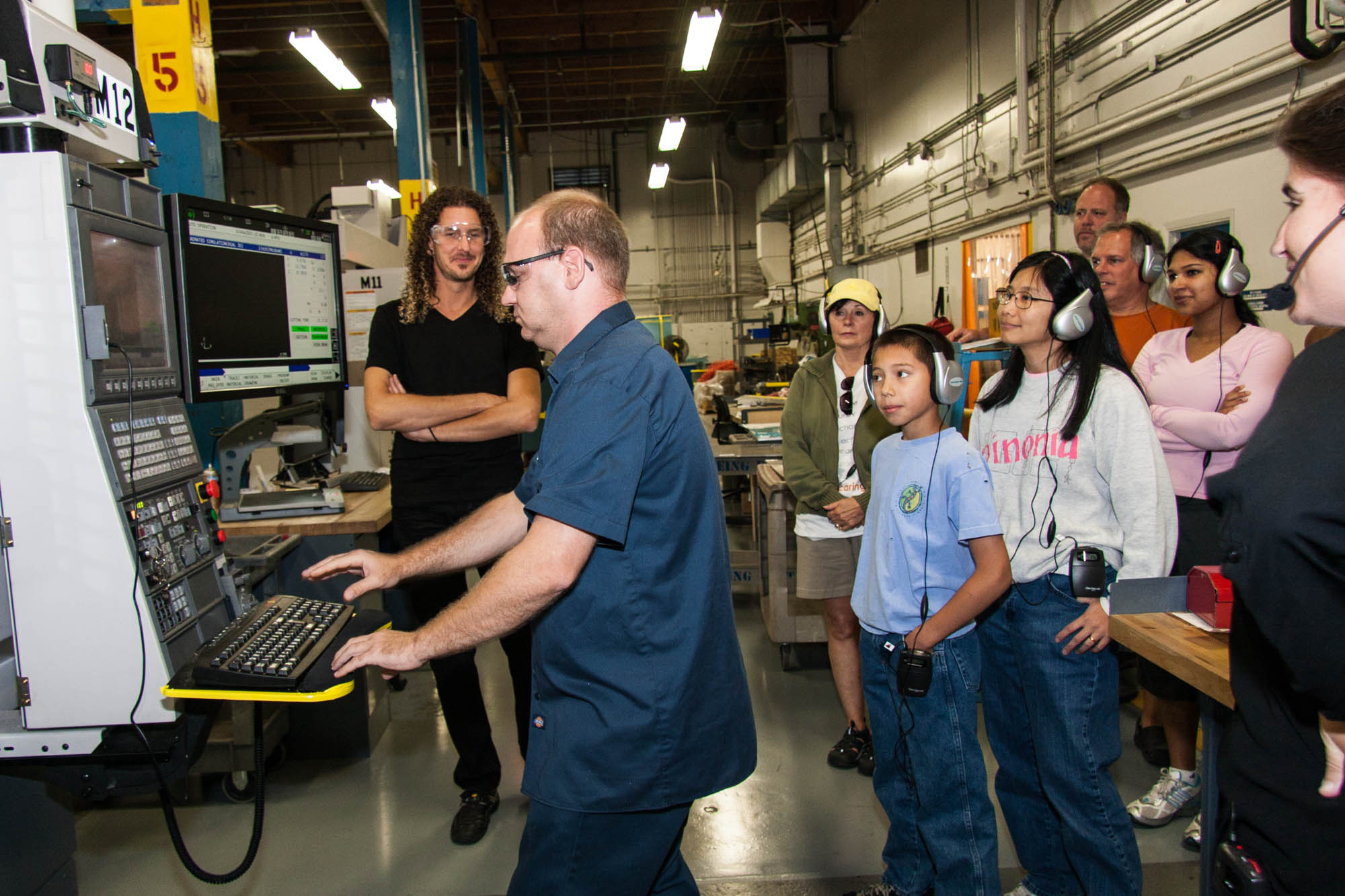 Lighthouse Set-Up Machinist Chris Loomis (left) demonstrating his Okuma CNC machine to a tour group from Microsoft