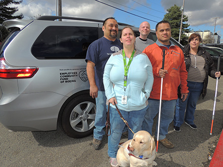 Lighthouse employees riding and standing outside of the new van provided by a grant from the Employees Community Fund of Boeing Puget Sound.