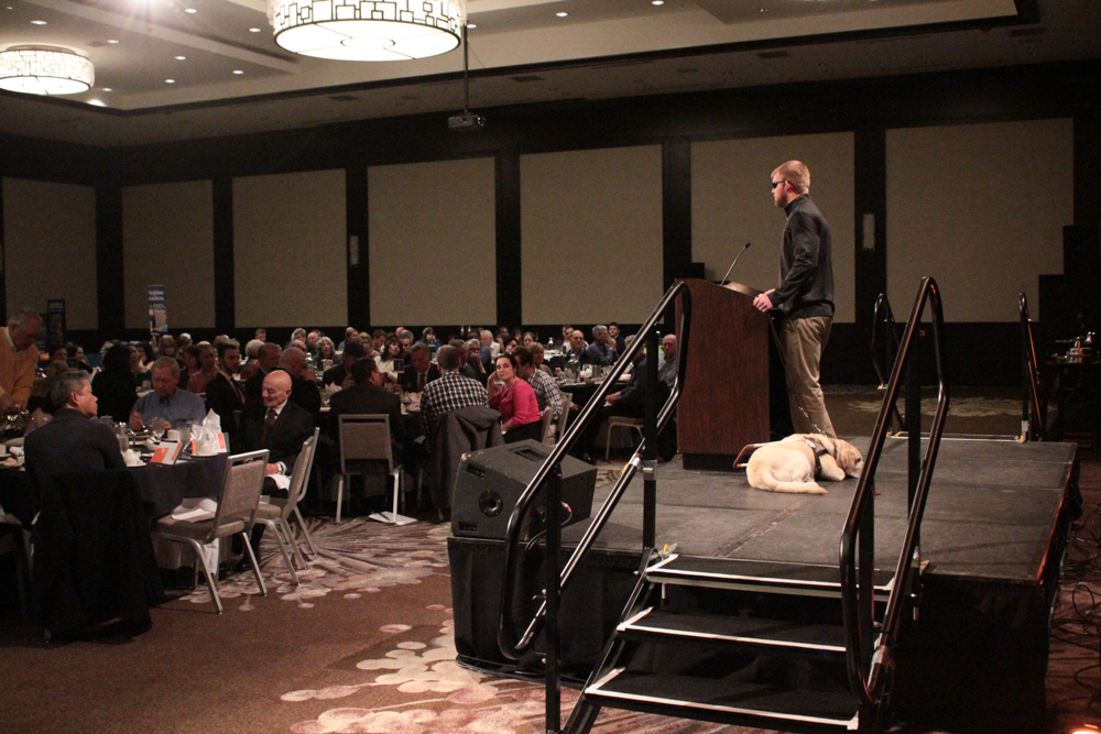 Keynote speaker Jake Olson (right) speaks to the audience at the Luncheon