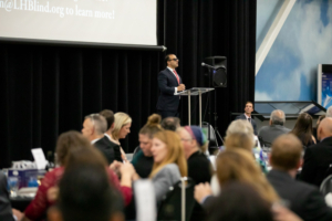 wide view of man speaking with people at tables