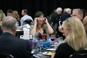 woman putting on glasses at table