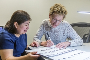 Jane Elliott (right) shows Nhi Porter (left) how to use a large print calendar