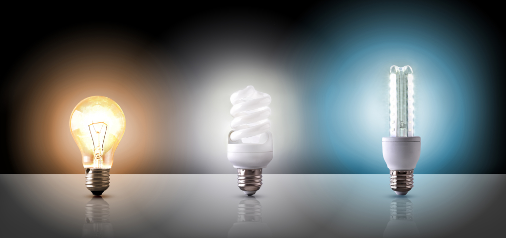 A photo of three different types of light bulbs. The one on the left is giving off yellow light, the one in the middle white light, and the one on the right blue light.