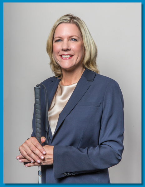 Portrait of President and CEO Cindy Watson, a light skinned, blonde haired woman holding a white cane.