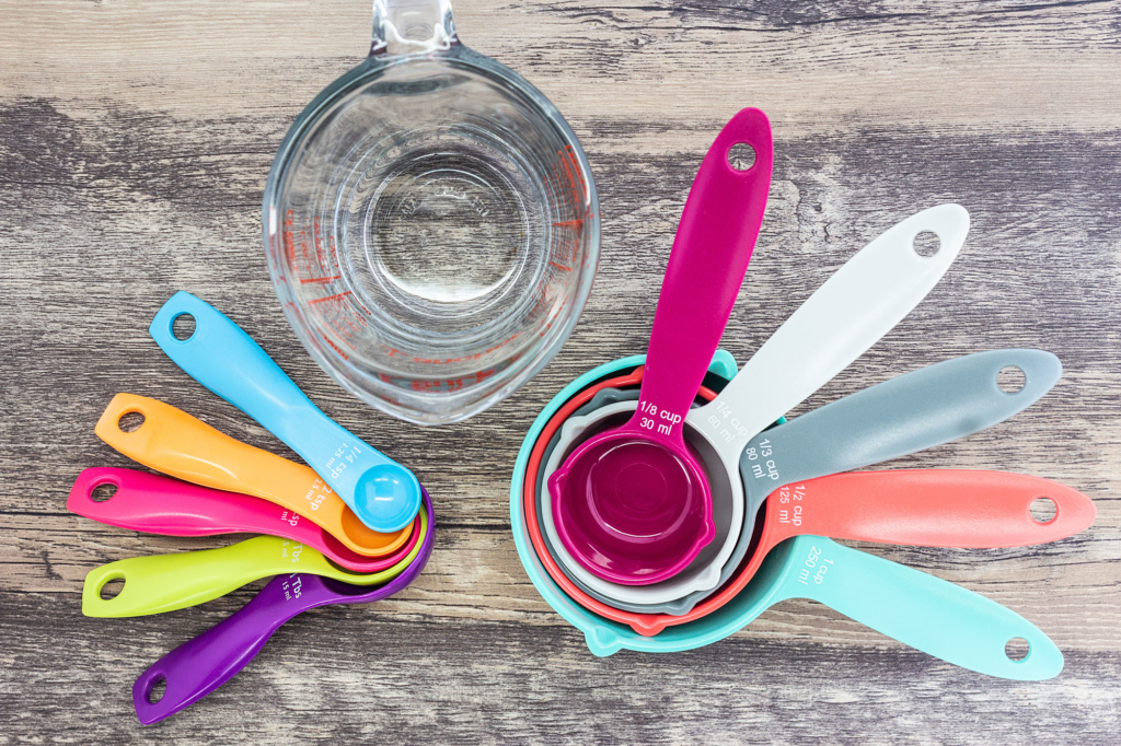 Sets of kitchen measuring tools including a glass cup, and plastic spoons and cups nested together