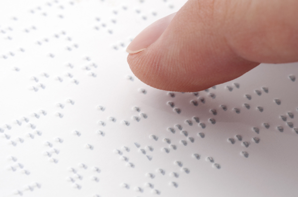 A close up of a finger on a braille page.