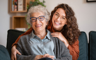 A portrait of two women wearing glasses, one is a young adult and the other elderly