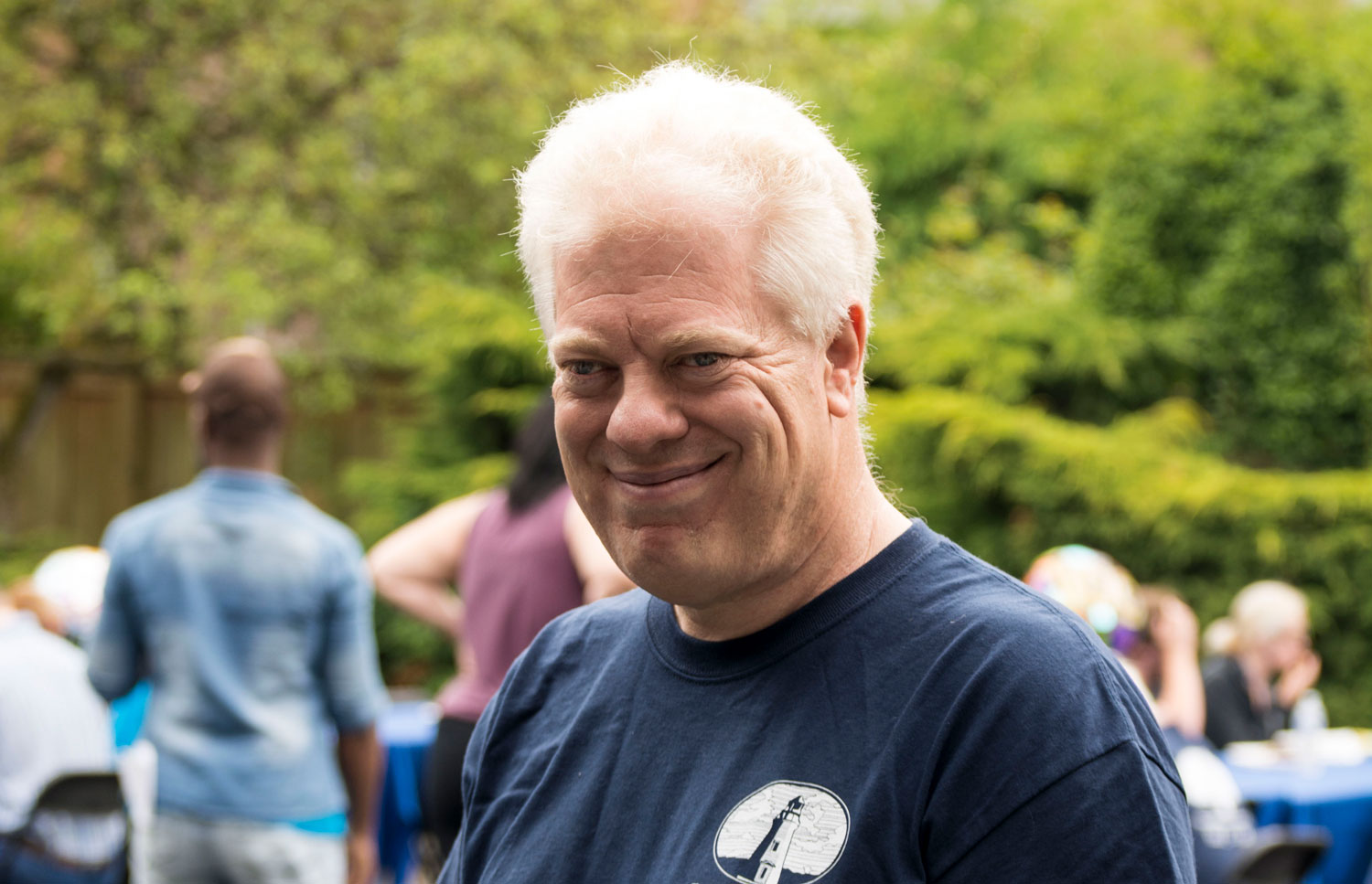 Portrait of Mike Scheschy, a light skinned man with white hair standing outside and smiling.