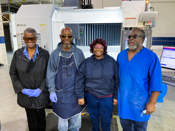 Summerville, SC production workers Sharon Dunbar, Dexter Gibbs, and Wanda Hartwell, alongside Production Lead Roosevelt Stevenson, stand next to an Okuma CNC machine.