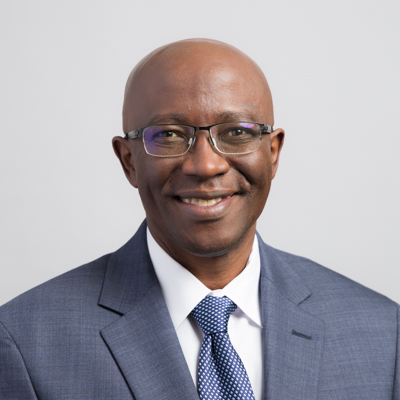 Photo of Paul, a dark-skinned man with glasses, wearing a suit and tie and smiling