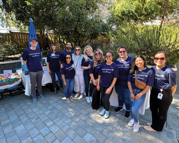 Volunteers from Bank of America's Disability Action Network. A group of 11 people stand outside in a garden, wearing matching dark blue t-shirts and smiling.