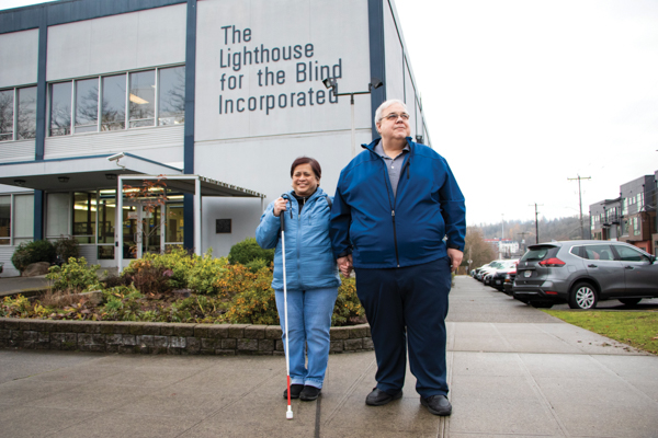 Ursula McCully, Production Worker, and Glenn McCully, Senior Human Resources manager stand outside in front of the Seattle facility holding hands.