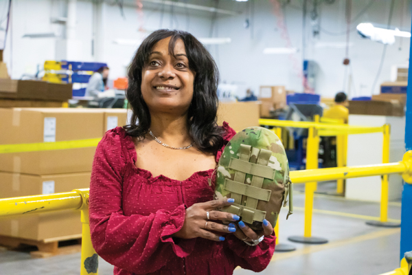 Photo of Trieva, a dark-skinned woman holding up a canteen on the production floor of the Seattle facility
