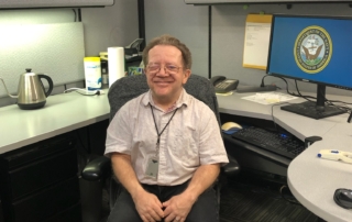 Michael Dunn sitting at his Contract Management Services work station.