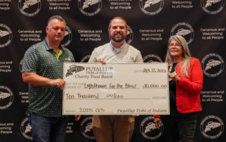 Two men and one woman hold an oversized check in the amount of $10,000