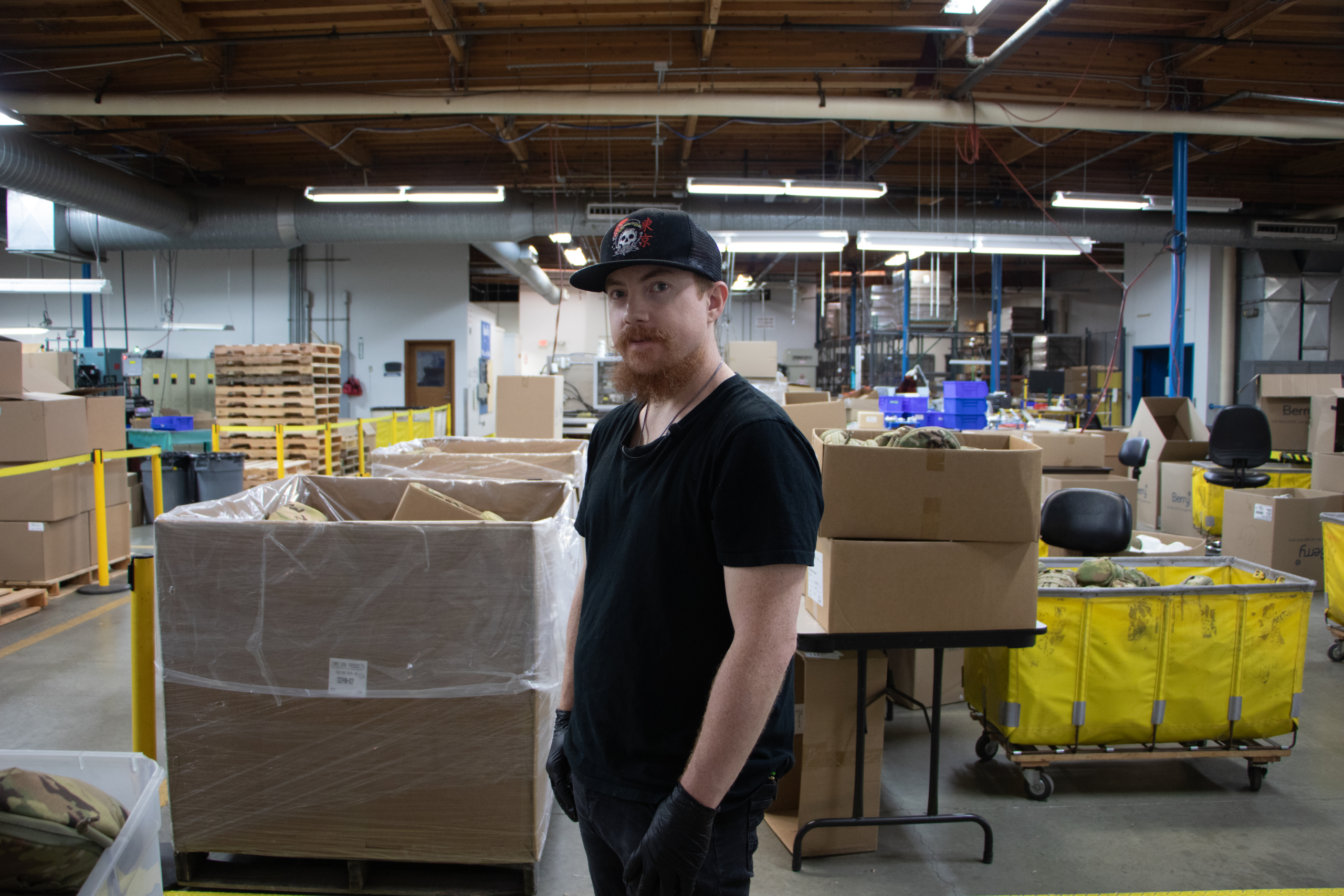 Gregory Wilson standing on the Manufacturing floor, with boxes all around him.