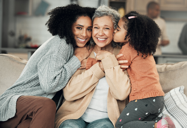 Stock image of three generations of women sitting on a couch - mother, grandmother, and granddaughter