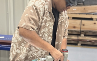 A man uses a hydraulic nail gun to assemble a wallboard.