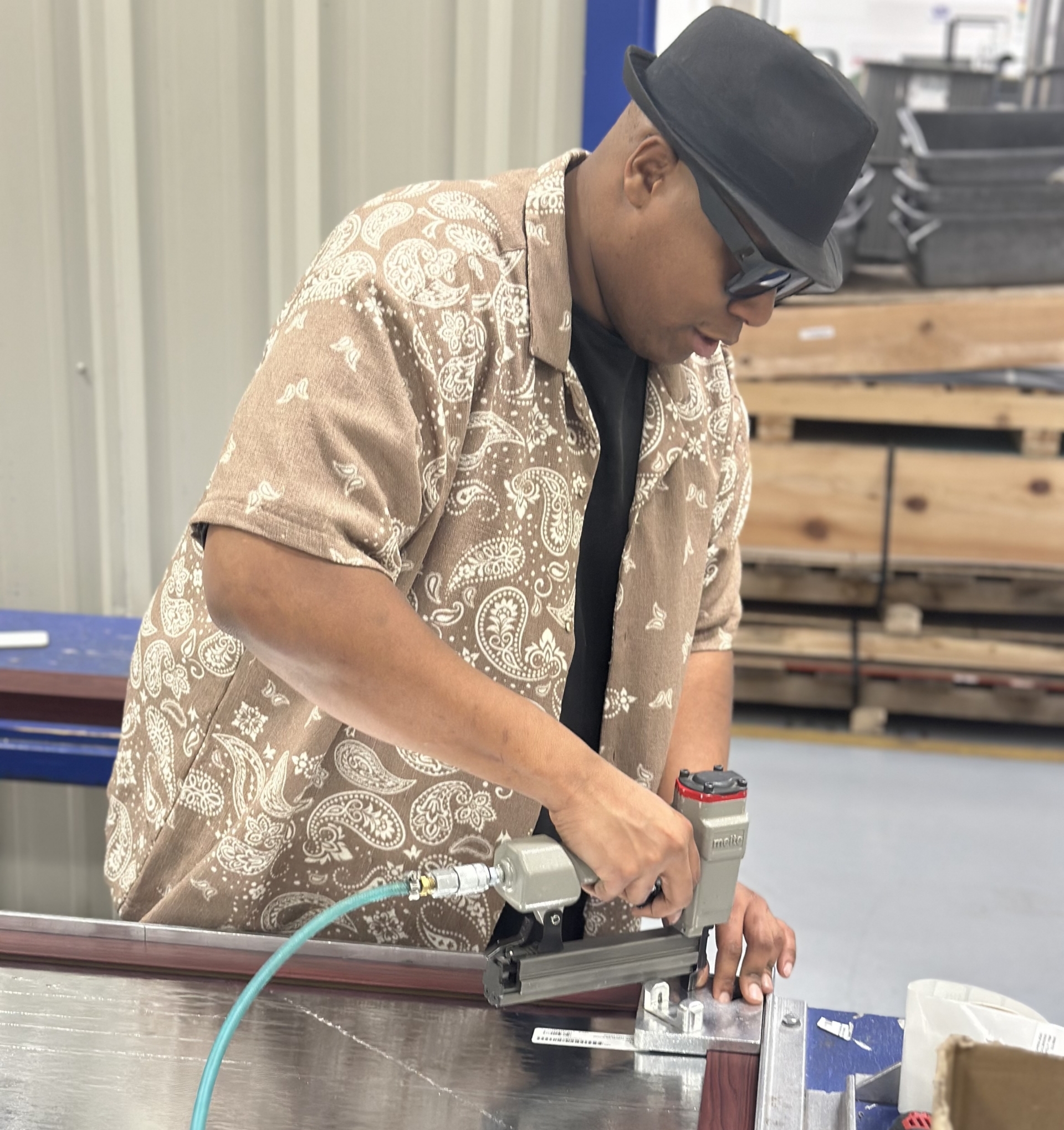 A man uses a hydraulic nail gun to assemble a wallboard.