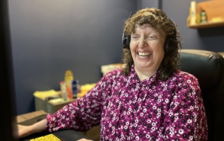 Melinda Slovernick at her workstation, with her hands on the keyboard, smiling.
