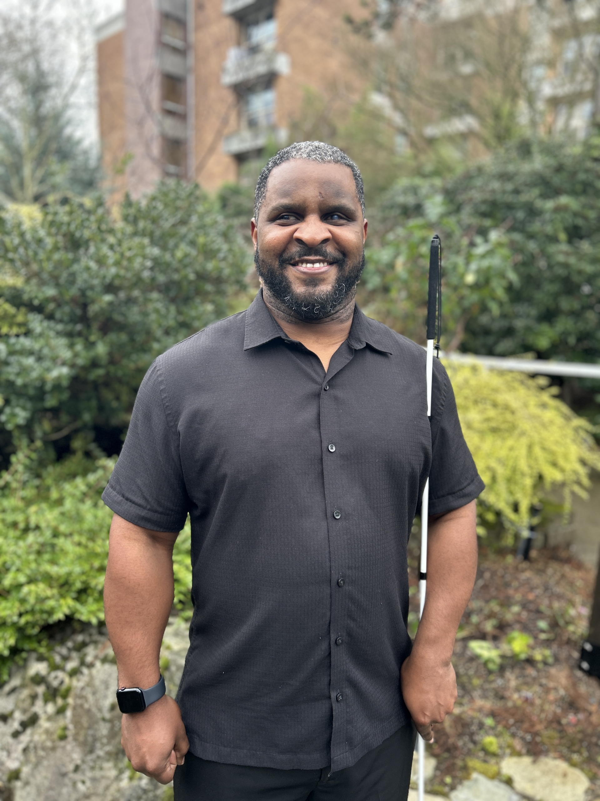 Antonio Rozier stands in a garden with a white cane, smiling.
