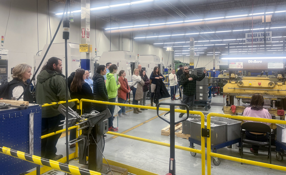 Attendees of the Employment for Empowerment event watch Robert Fair demonstrating the life of a wallboard in the Spokane facility