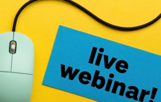 A green computer mouse with a sign that says, "live webinar"